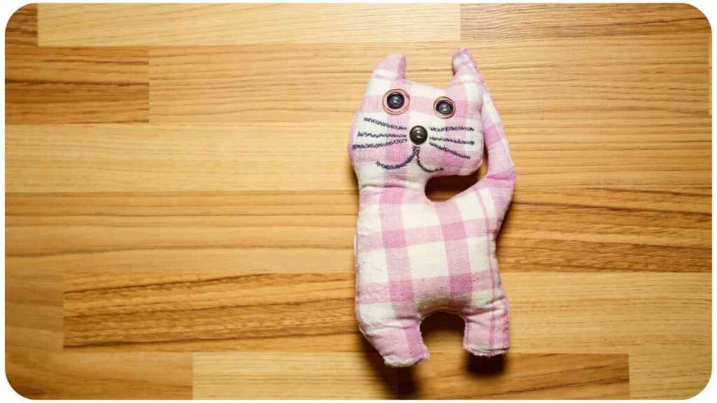 a pink and white checkered cat toy sitting on a wooden floor