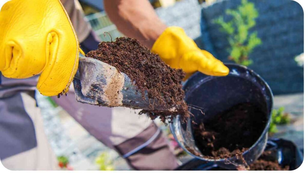 a person in yellow gloves is using a shovel to spread dirt